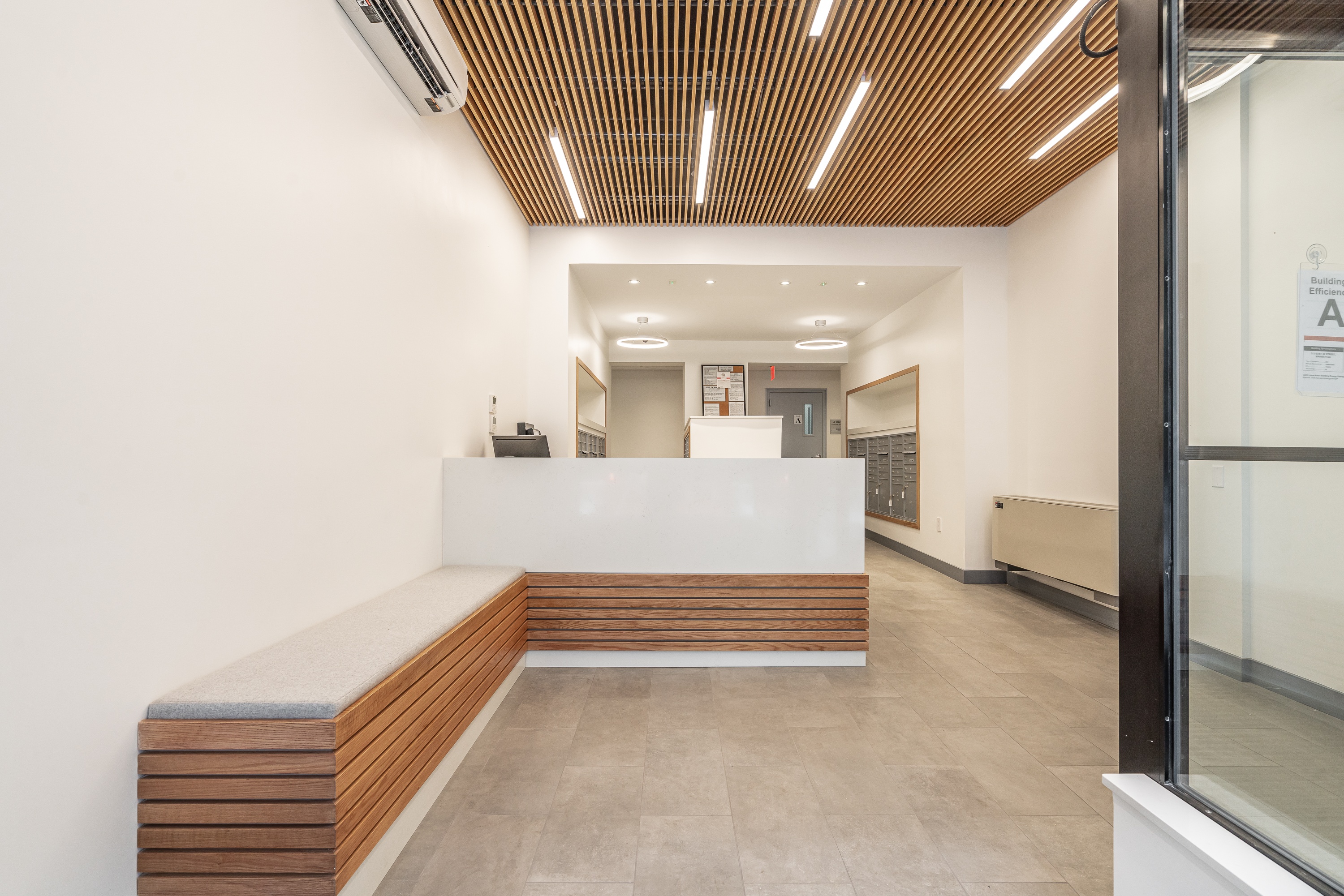 A reception area with a white counter and a wooden bench.